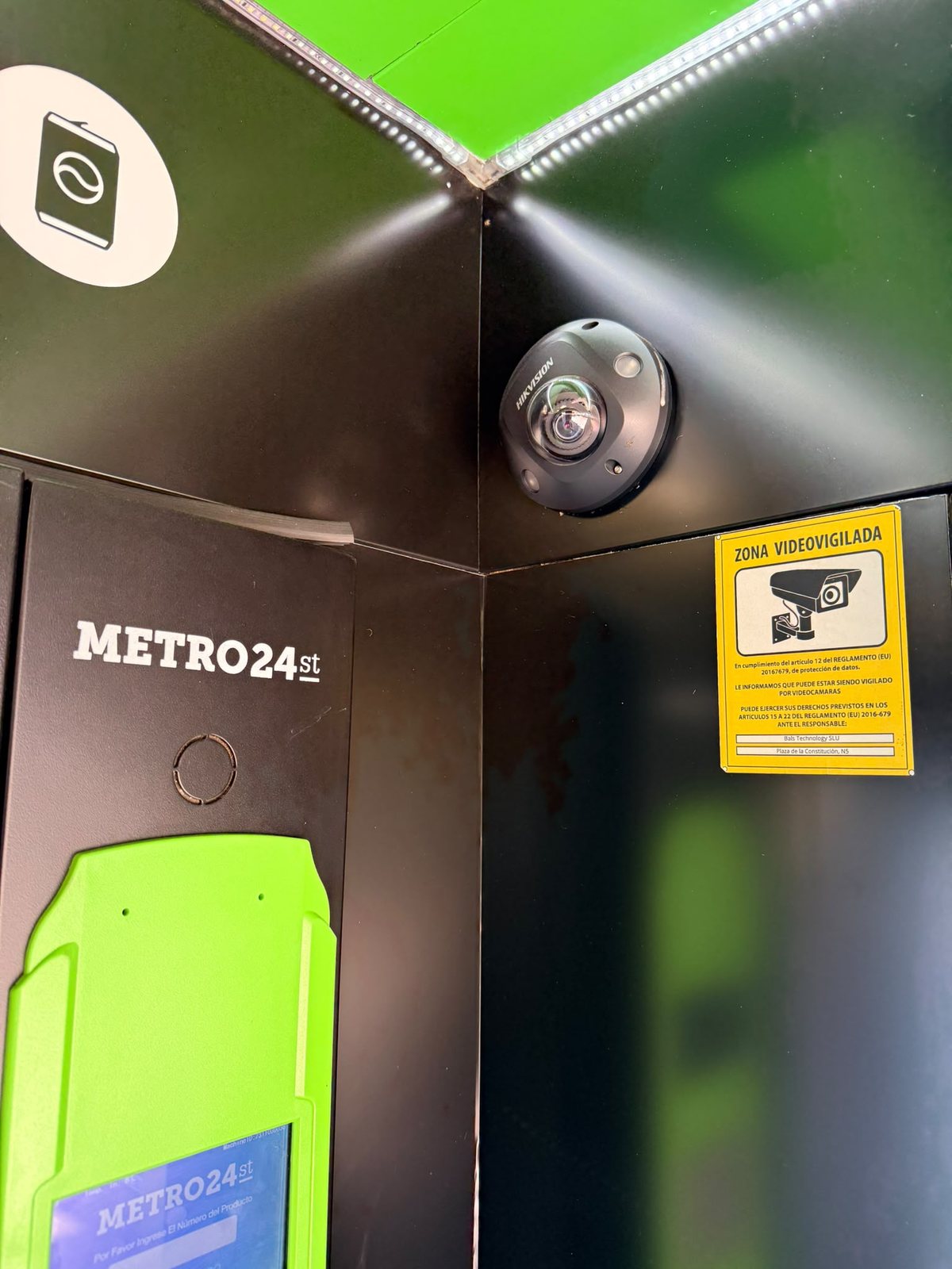 Cámara de vigilancia con cartel de zona videovigilada en máquina de vending